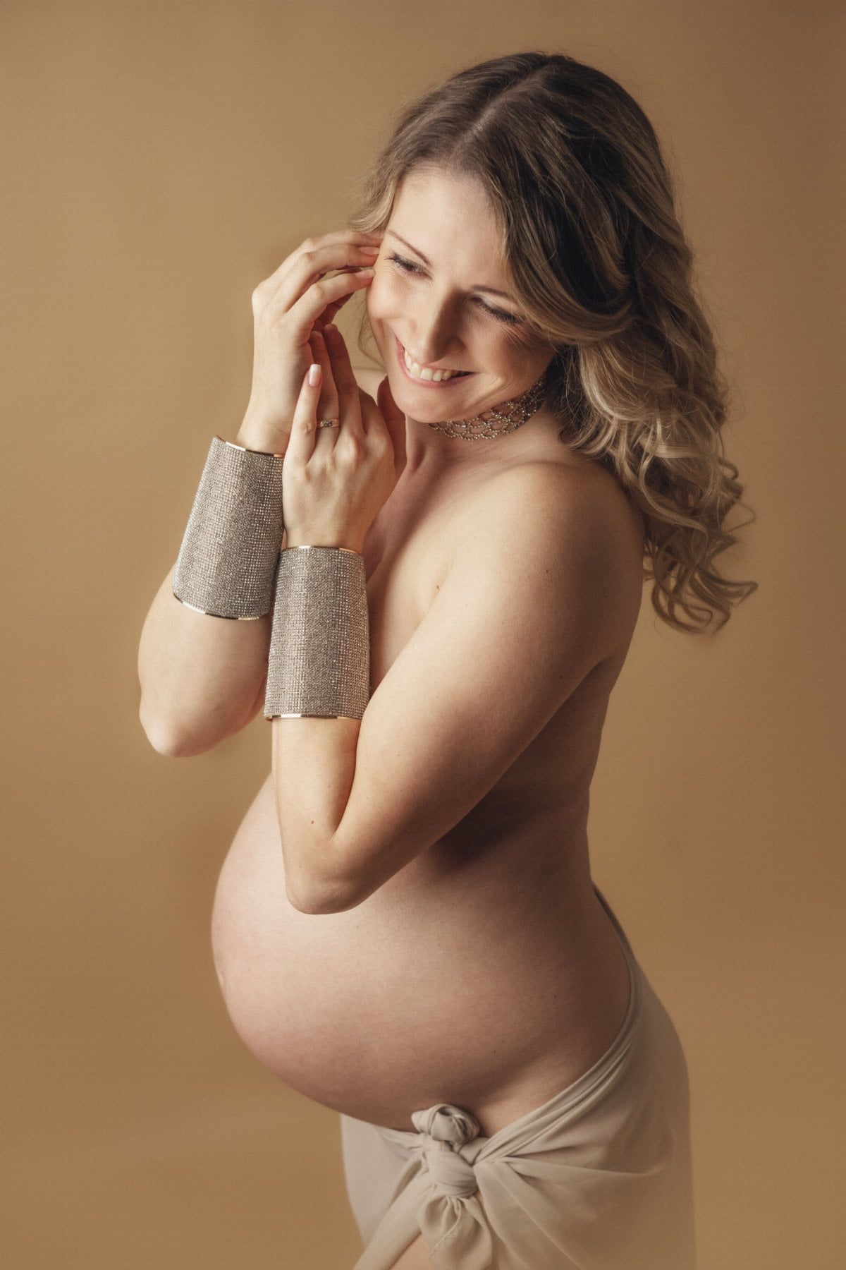 Babybauch Shooting in Hamburg. Das Bild zeigt eine junge Frau die die Arme vor den Brünsten hat und den Bauch frei.