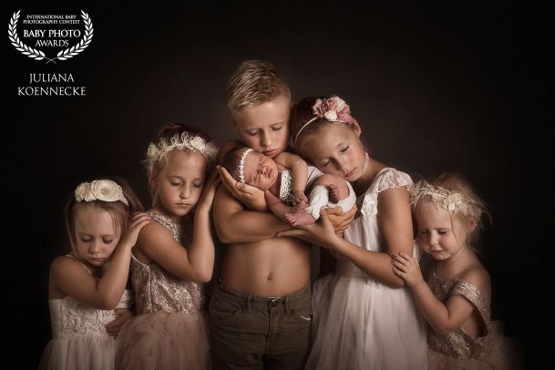 Fünf Kinder stehen nebeneinander. In der Mitte der älteste Bruder, rechts und links daneben jeweils zwei Schwestern, die nach außen hin kleiner werden. Auf dem Arm trägt der Junge ein neugeborenes Baby.