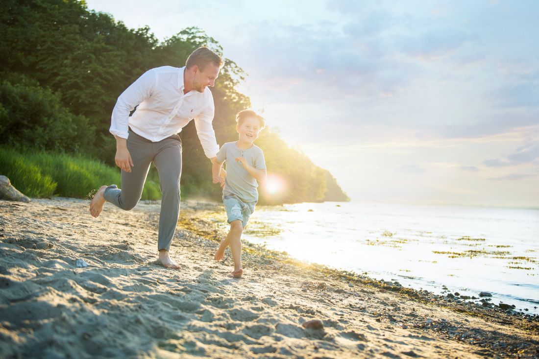 Vater und Sohn laufen am Strand entlang. Im Hintergund das Meer in Glücksburg und Flensburg.